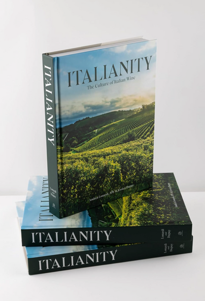 Stack of books titled 'Italianity' on a white surface with a vineyard image on the cover.