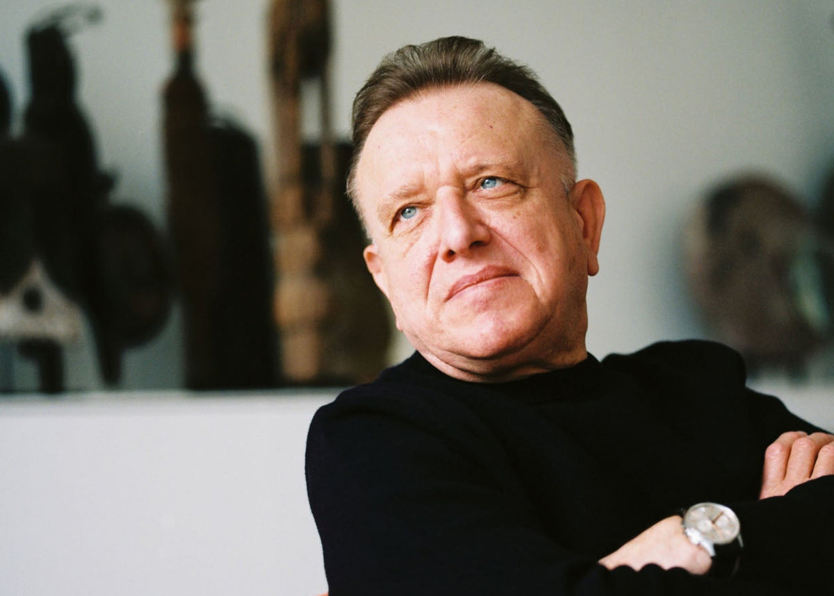 Richard Geoffroy sitting on an orange chair wearing a black top with folded arms. 